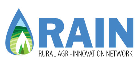Rural Agri-Innovation Network logo text shows three nested teardrop shapes: largest is blue, middle shows green horizontal curves, and the smallest has three coniferous trees.